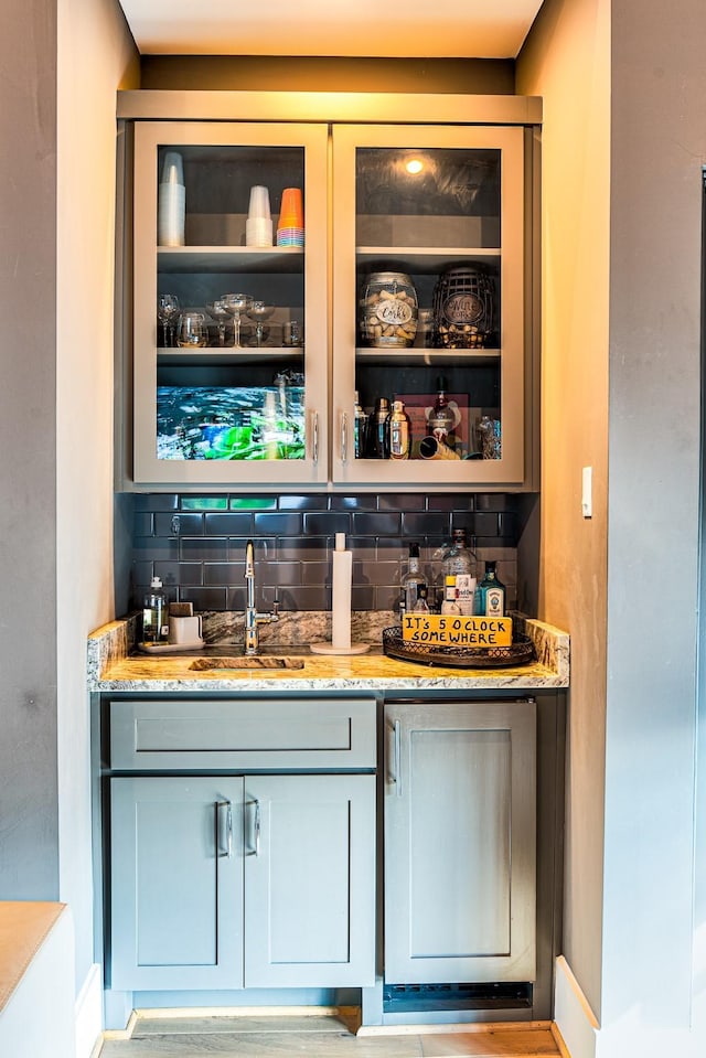 bar featuring tasteful backsplash, wet bar, and a sink