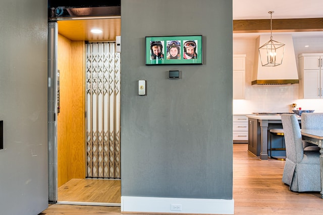 details with tasteful backsplash, elevator, wood finished floors, beamed ceiling, and premium range hood