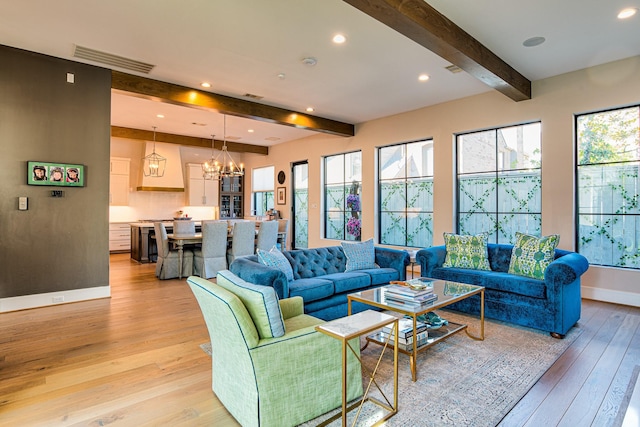 living area with plenty of natural light, visible vents, beamed ceiling, and light wood finished floors