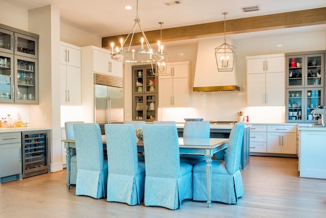 dining room featuring wine cooler, light wood-type flooring, beam ceiling, and visible vents