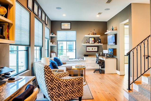 office space with light wood finished floors, built in desk, and visible vents