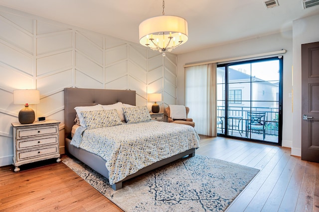 bedroom with access to exterior, visible vents, and wood finished floors