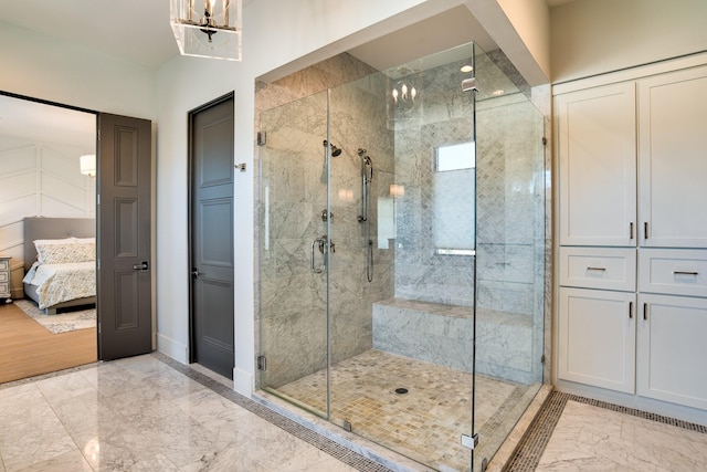 full bath with a notable chandelier, baseboards, marble finish floor, a stall shower, and ensuite bath