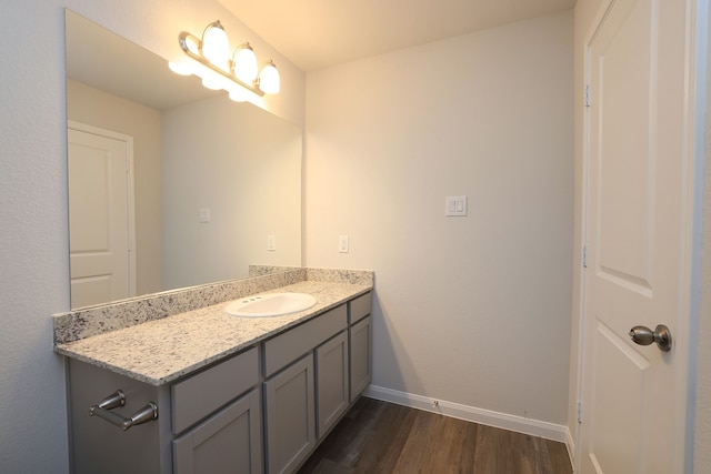 bathroom with vanity, wood finished floors, and baseboards
