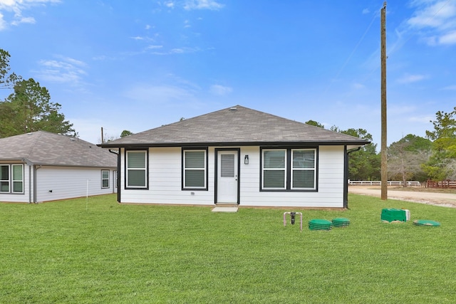 view of front of property featuring a front lawn and roof with shingles