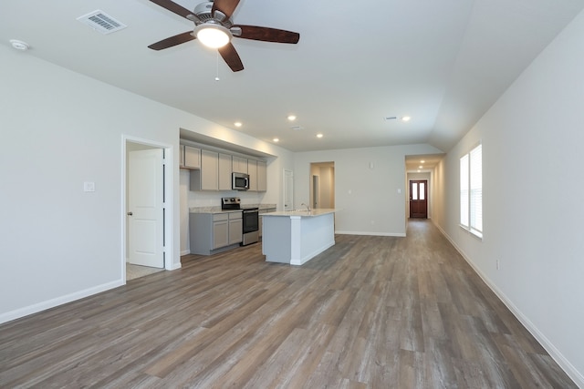 kitchen with visible vents, an island with sink, gray cabinetry, appliances with stainless steel finishes, and open floor plan