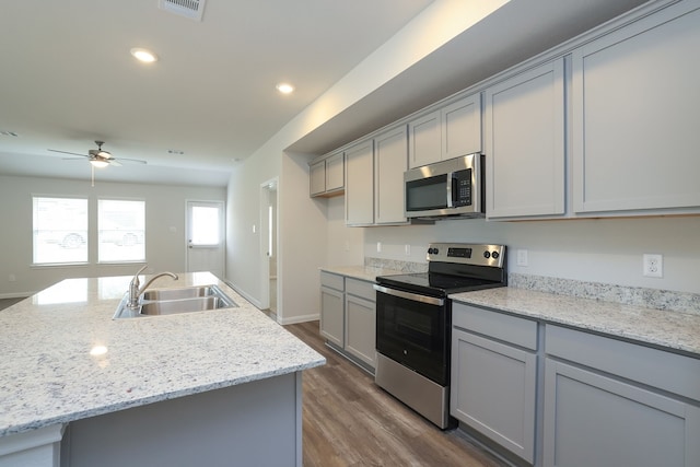 kitchen featuring appliances with stainless steel finishes, dark wood-type flooring, gray cabinetry, and a sink
