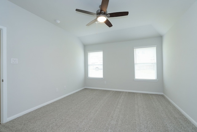 spare room with vaulted ceiling, carpet, baseboards, and ceiling fan