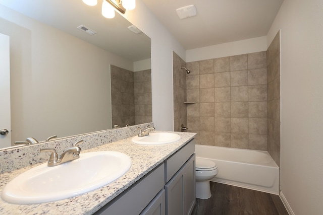 full bathroom featuring visible vents, toilet, wood finished floors, and a sink