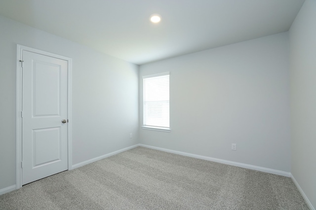 spare room with baseboards and light colored carpet