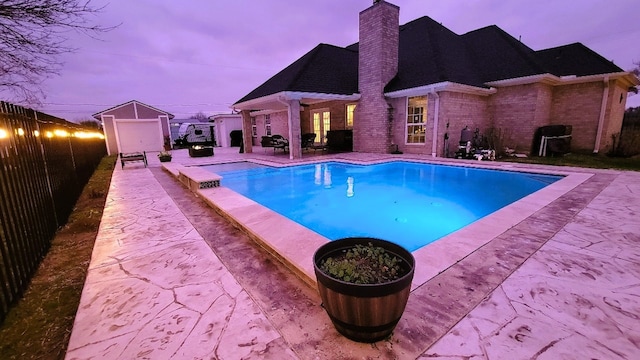 pool at dusk featuring a patio