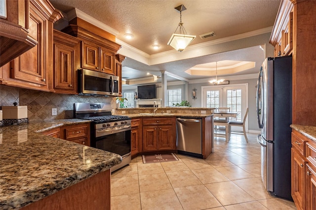 kitchen with a tray ceiling, sink, hanging light fixtures, kitchen peninsula, and stainless steel appliances