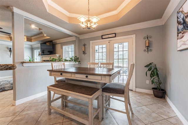 tiled dining area featuring crown molding, a tray ceiling, plenty of natural light, and an inviting chandelier