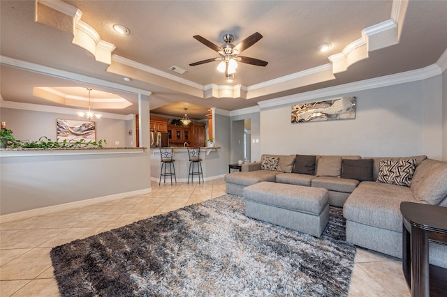 tiled living room with a raised ceiling, ornamental molding, and ceiling fan with notable chandelier