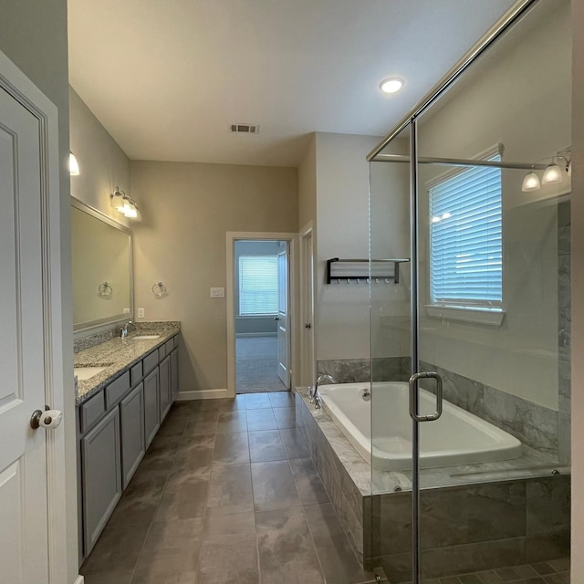 full bath featuring double vanity, visible vents, a bath, tile patterned floors, and a sink