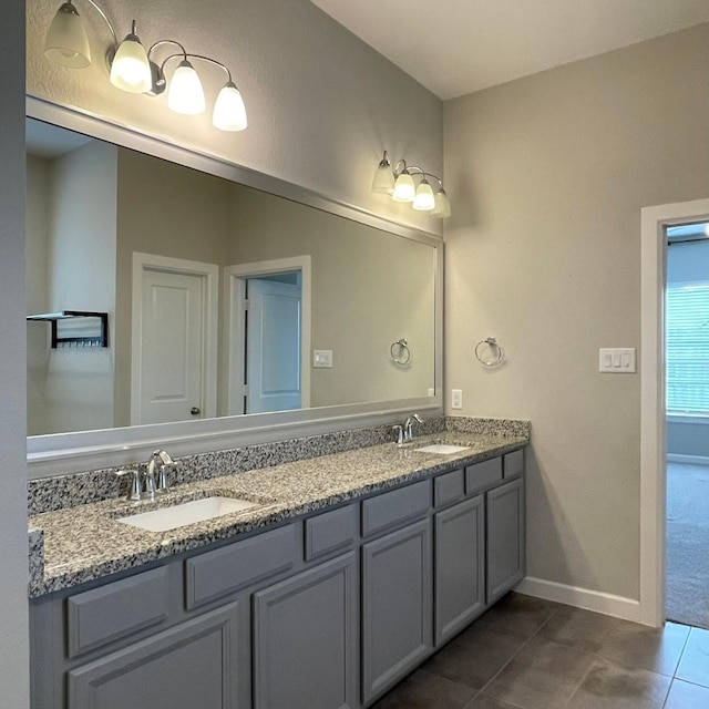 full bathroom with double vanity, tile patterned flooring, baseboards, and a sink