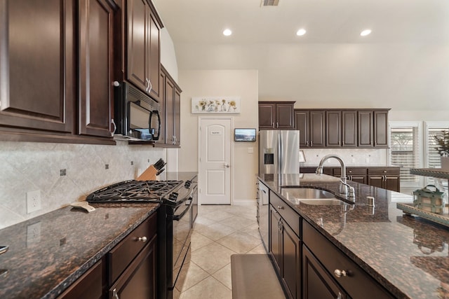 kitchen featuring dark brown cabinetry, sink, dark stone counters, and black appliances