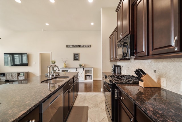 kitchen featuring sink, dark stone counters, dark brown cabinetry, and black appliances