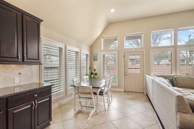 dining space with lofted ceiling, a healthy amount of sunlight, and light tile patterned floors