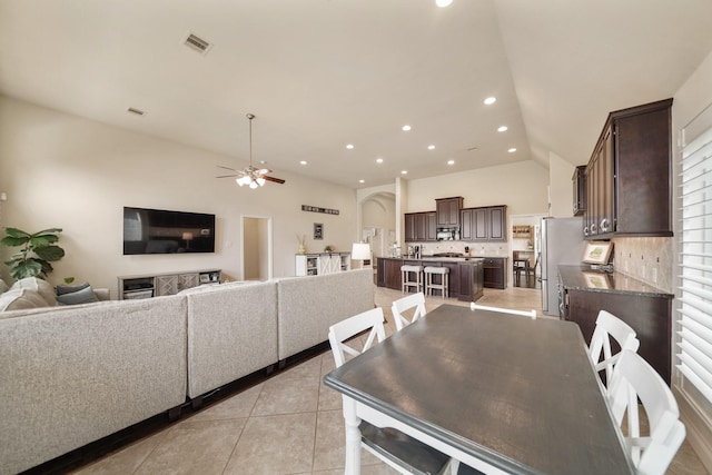 tiled dining area with ceiling fan and lofted ceiling