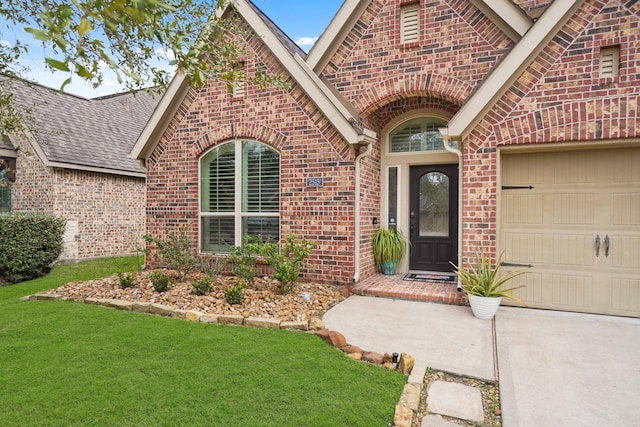 view of exterior entry featuring a garage and a lawn