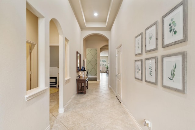 hallway with a towering ceiling and light tile patterned flooring