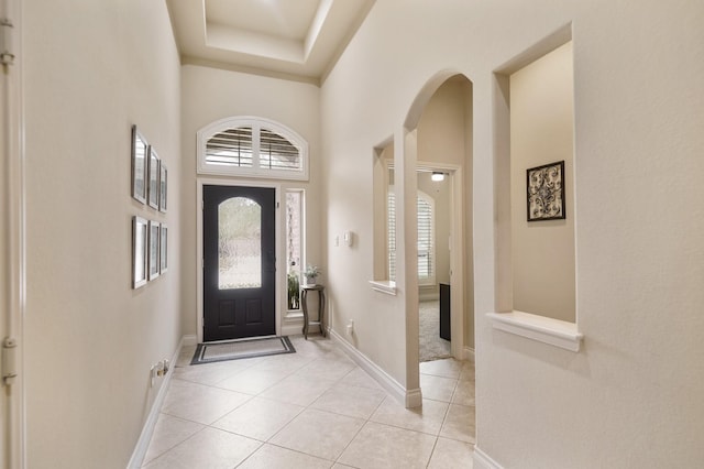 tiled entrance foyer with a towering ceiling and a raised ceiling