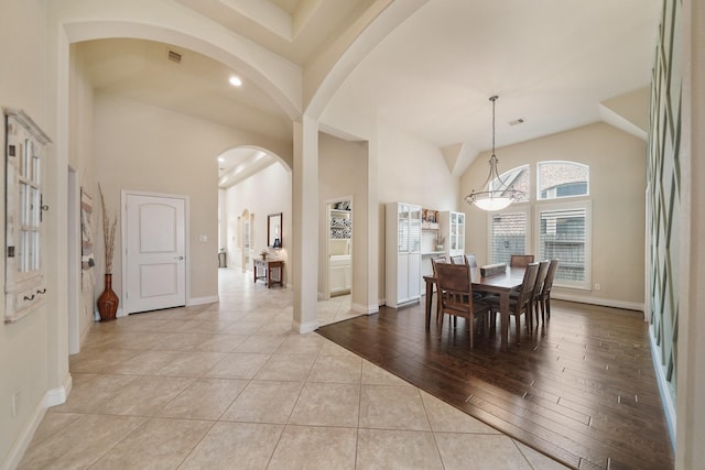 dining area with high vaulted ceiling and light hardwood / wood-style flooring