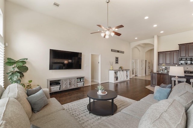 living room featuring dark hardwood / wood-style flooring, a towering ceiling, and ceiling fan