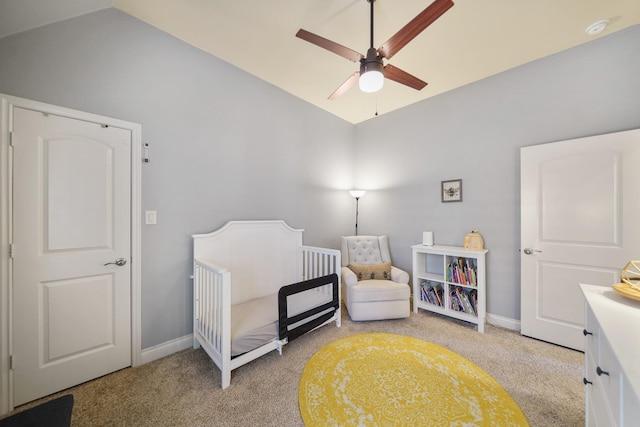 carpeted bedroom with vaulted ceiling, a nursery area, and ceiling fan