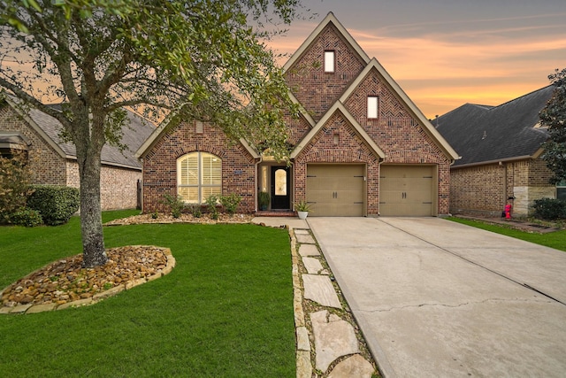 tudor home featuring a garage and a yard