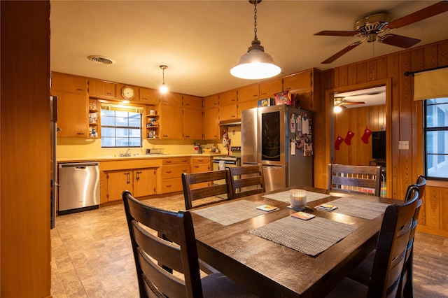 dining room with sink, ceiling fan, and wood walls