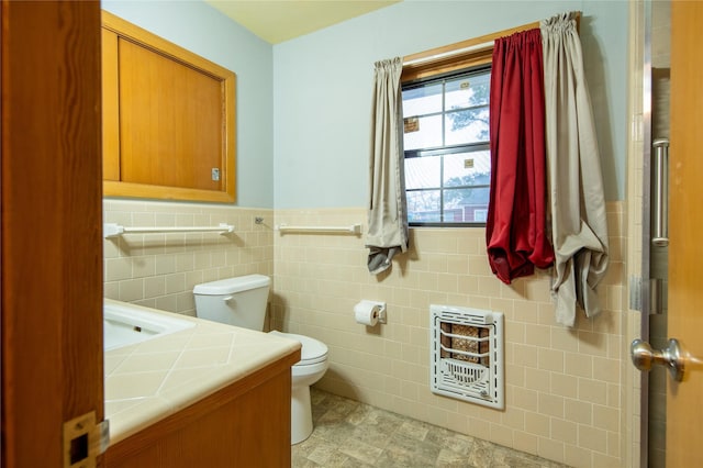 bathroom featuring vanity, heating unit, tile walls, and toilet