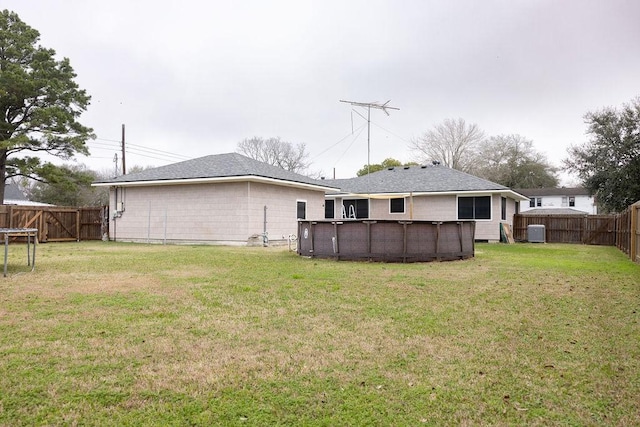 back of property featuring a fenced in pool, central AC unit, and a lawn