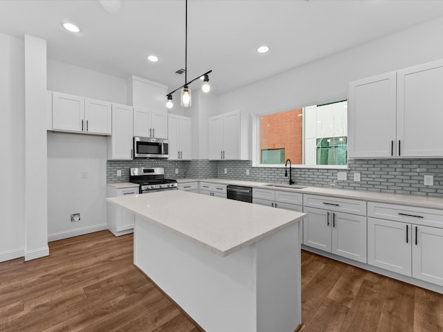 kitchen with white cabinetry, hanging light fixtures, a kitchen island, and appliances with stainless steel finishes