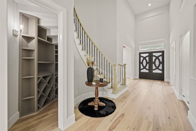 foyer entrance featuring french doors, a high ceiling, and light wood-type flooring