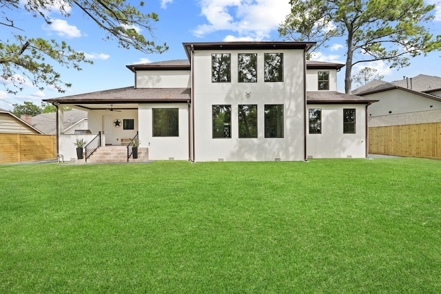 back of property featuring a yard and ceiling fan