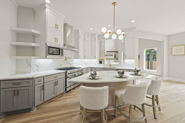 kitchen with wall chimney range hood, sink, appliances with stainless steel finishes, gray cabinetry, and white cabinetry