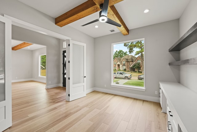 interior space featuring a healthy amount of sunlight, beam ceiling, and light hardwood / wood-style flooring