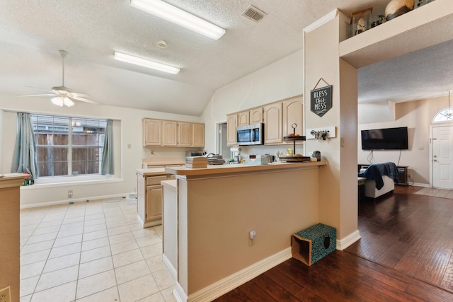 kitchen with lofted ceiling, light brown cabinetry, a textured ceiling, kitchen peninsula, and ceiling fan