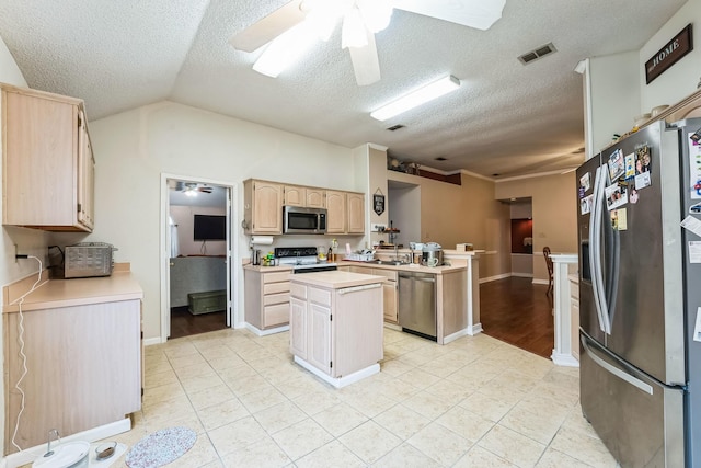 kitchen with light tile patterned flooring, a kitchen island, light brown cabinets, and appliances with stainless steel finishes