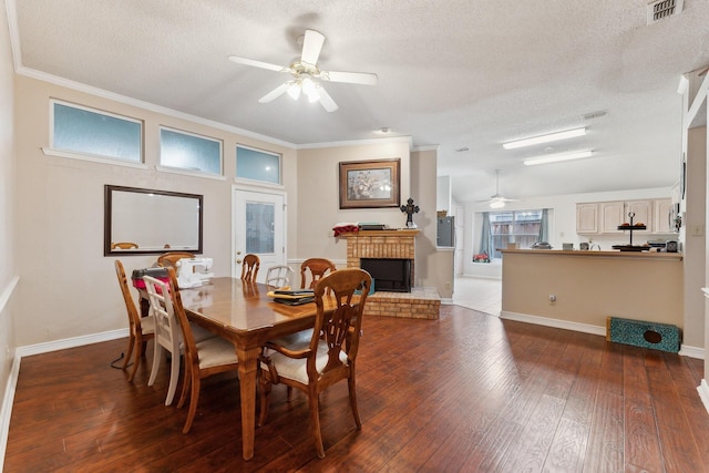 dining room with crown molding, hardwood / wood-style flooring, ceiling fan, a textured ceiling, and a brick fireplace