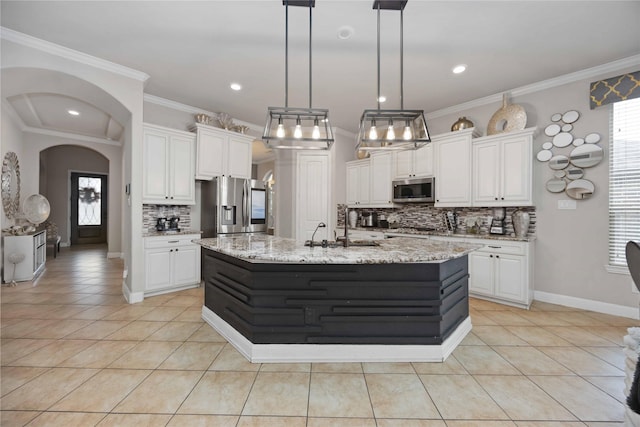 kitchen featuring white cabinetry, decorative light fixtures, stainless steel appliances, and a center island with sink