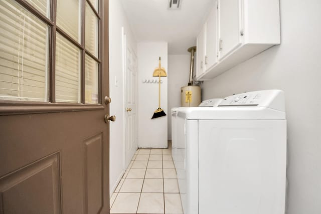 laundry room featuring light tile patterned floors, gas water heater, washing machine and dryer, and cabinets