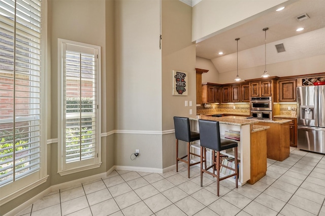 kitchen featuring appliances with stainless steel finishes, pendant lighting, a breakfast bar area, kitchen peninsula, and light stone countertops