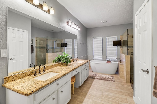 bathroom with vanity, a textured ceiling, and separate shower and tub