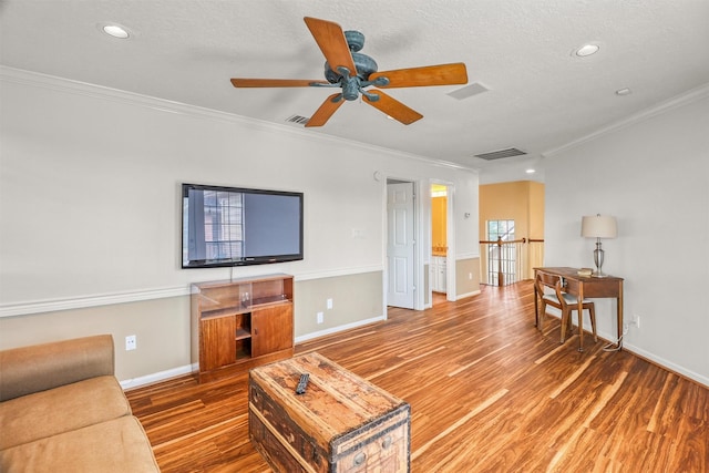 living room featuring hardwood / wood-style flooring, ceiling fan, ornamental molding, and a textured ceiling