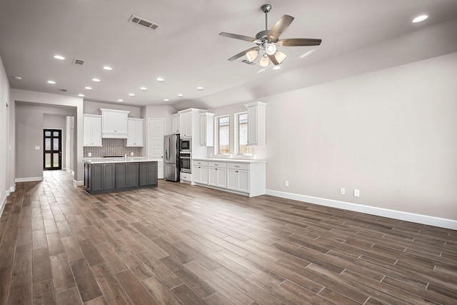 interior space featuring white cabinetry, appliances with stainless steel finishes, a center island, and backsplash