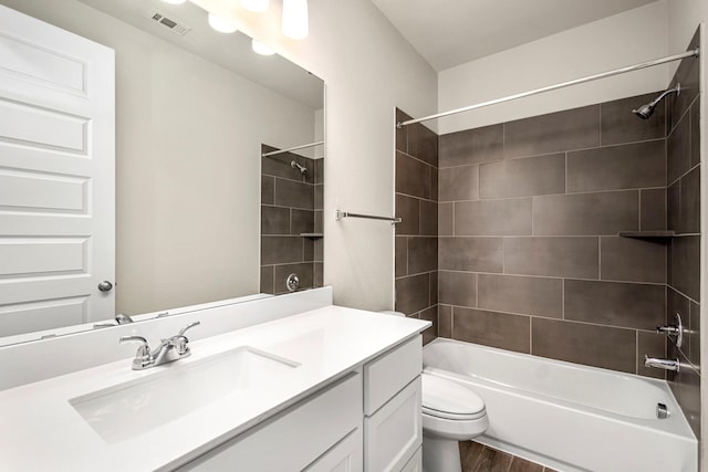 full bathroom featuring tiled shower / bath combo, vanity, hardwood / wood-style floors, and toilet