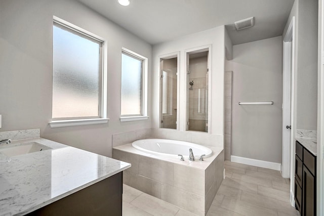 bathroom with tile patterned flooring, vanity, and plus walk in shower